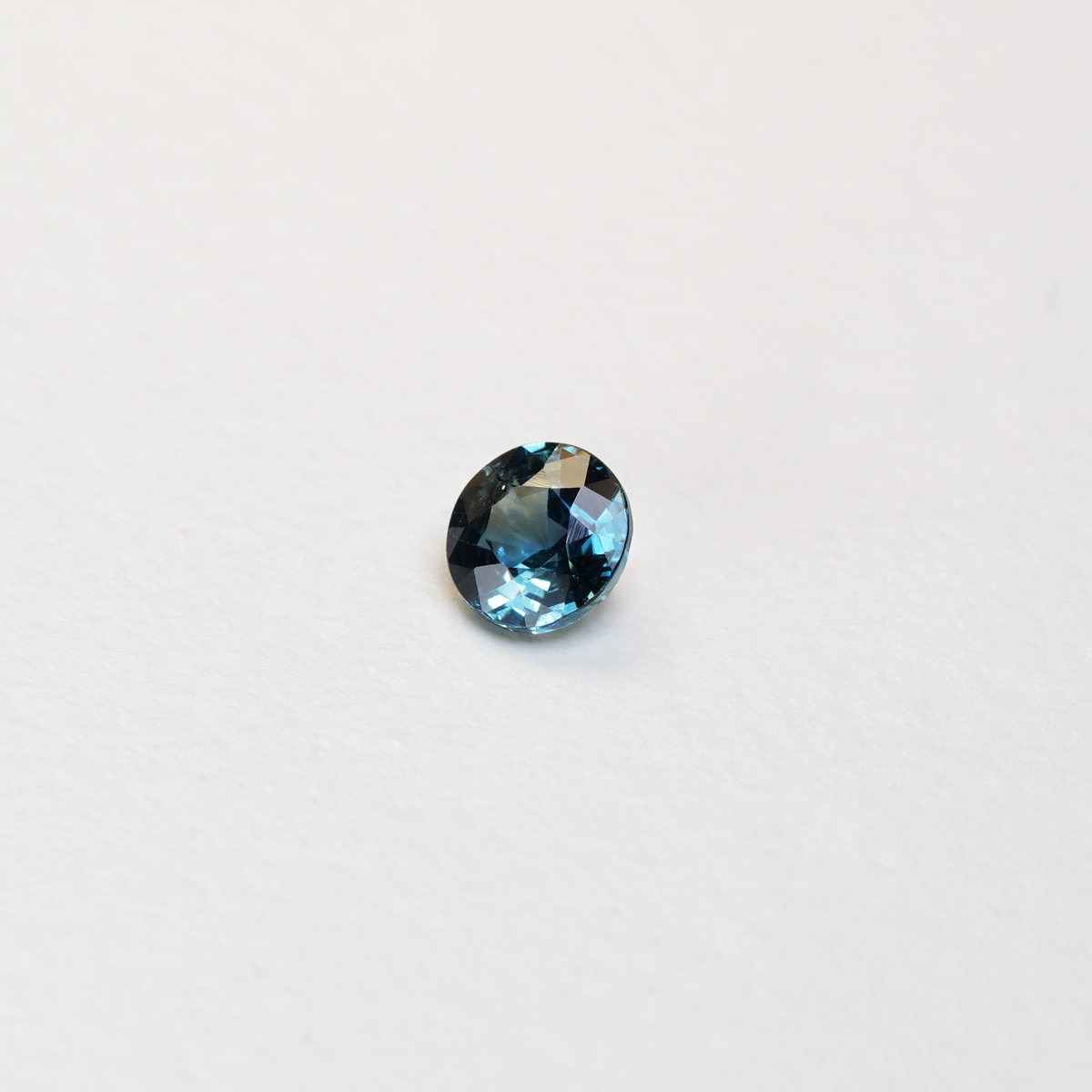 1 carat round parti teal sapphire with mixed green and blue color.