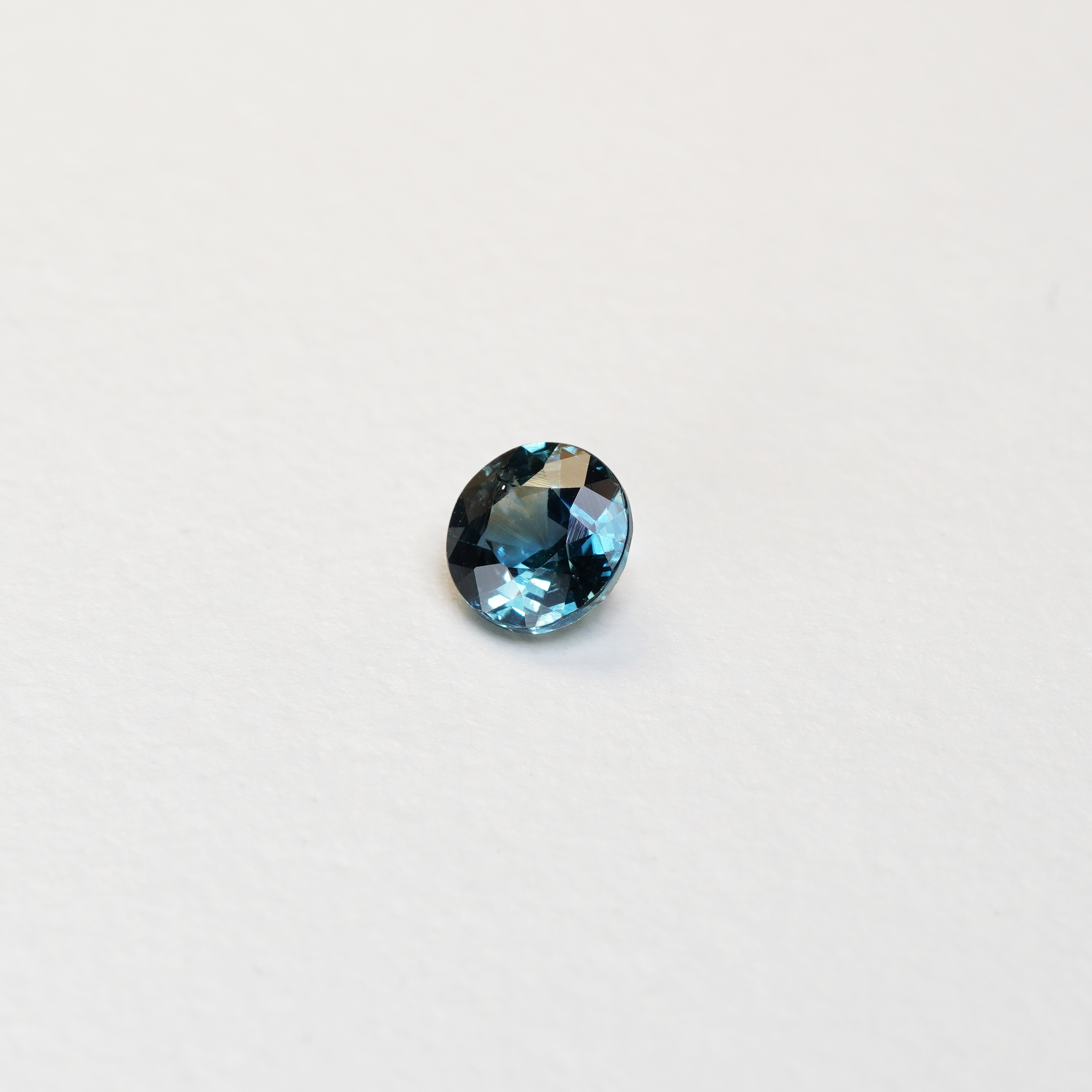 1 carat round parti teal sapphire with mixed green and blue color.