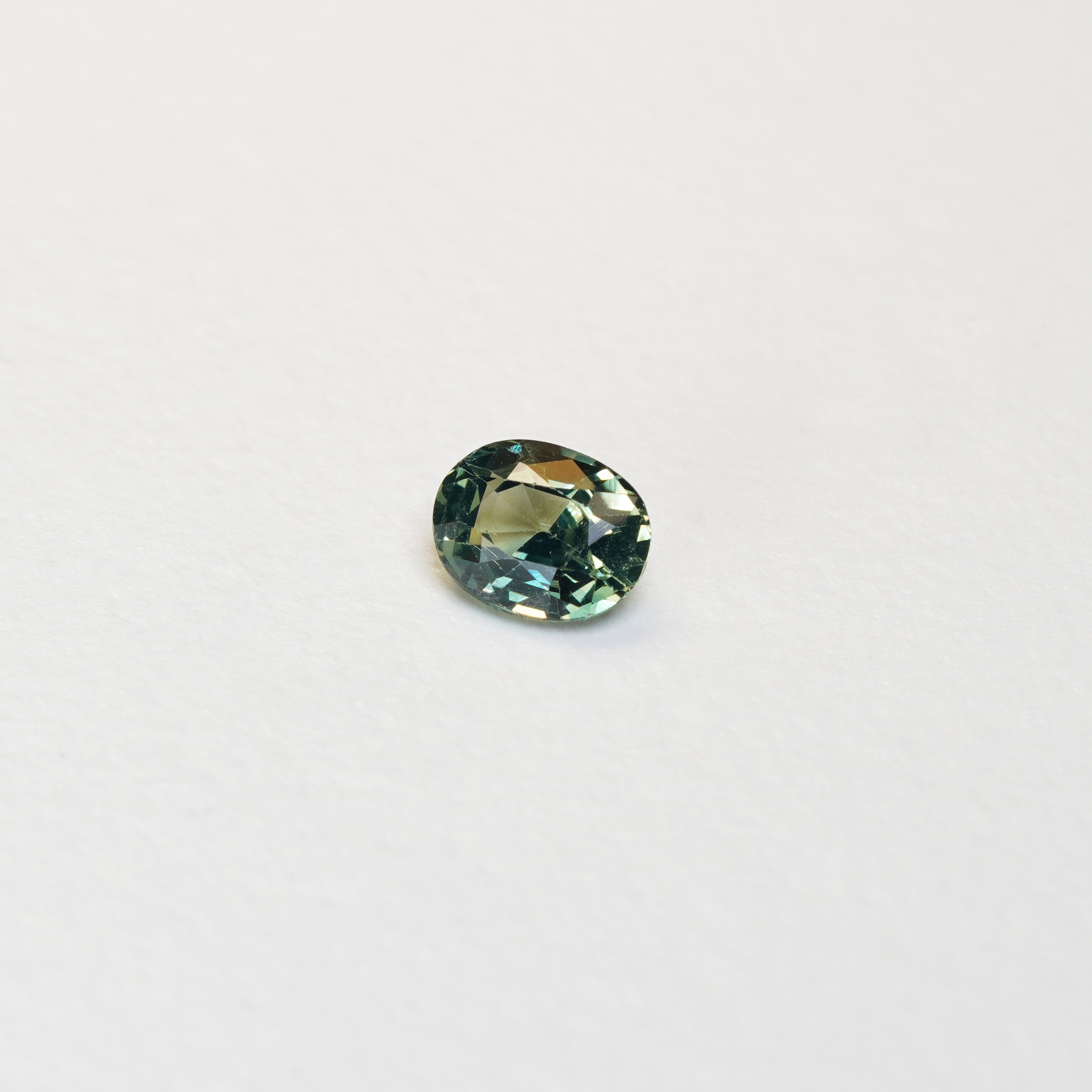 1.10 carat oval parti teal sapphire with mixed green and yellow color.