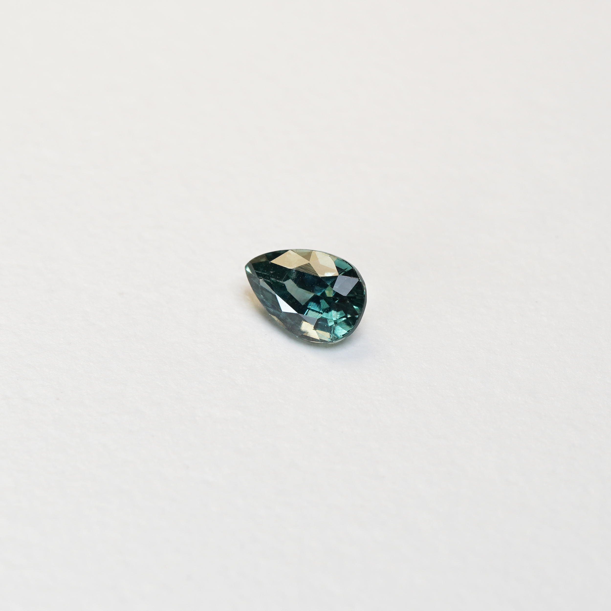 1.1 carat pear parti teal sapphire with mixed green and blue color.