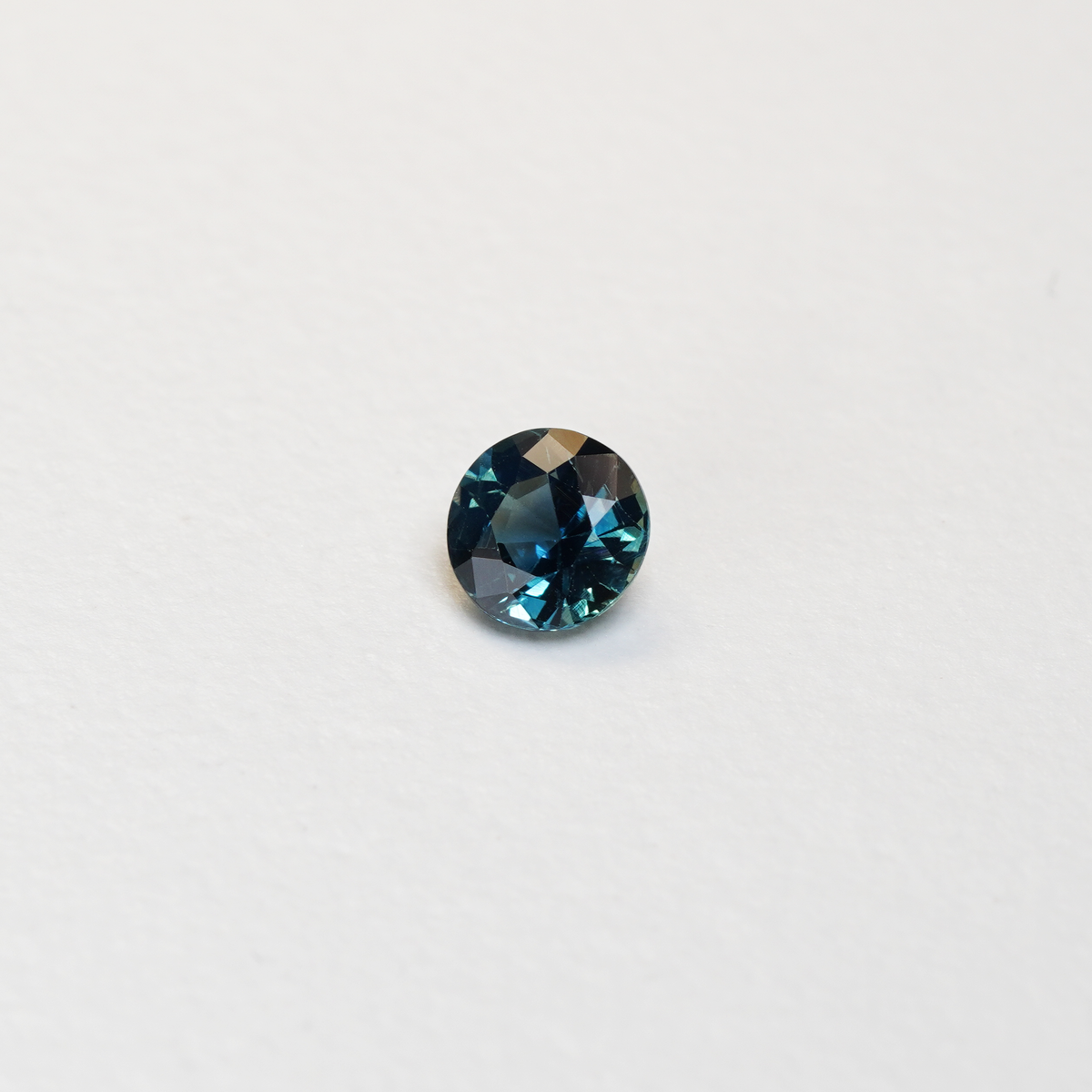 1.3 carat round parti teal sapphire with mixed green and blue color.