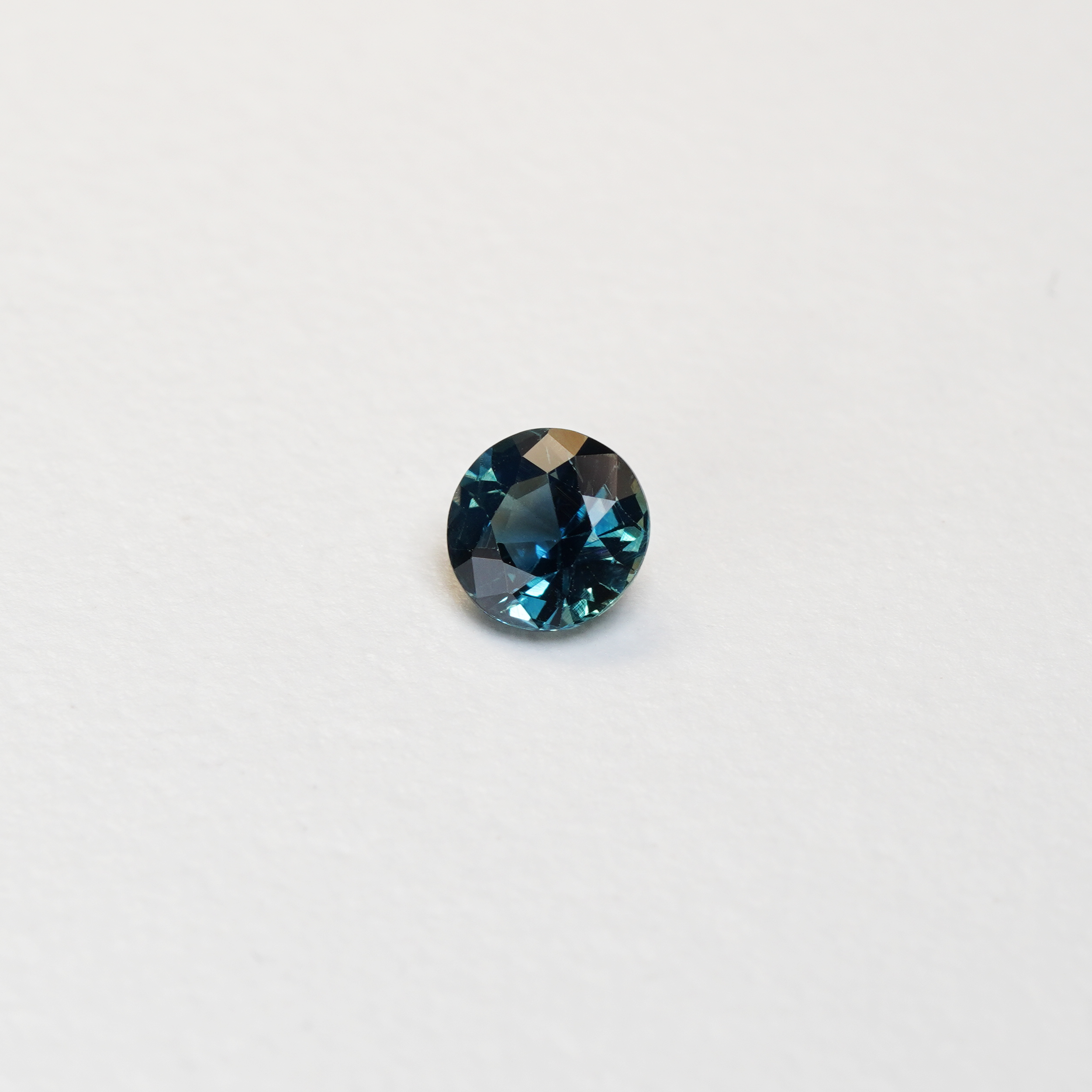 1.3 carat round parti teal sapphire with mixed green and blue color.