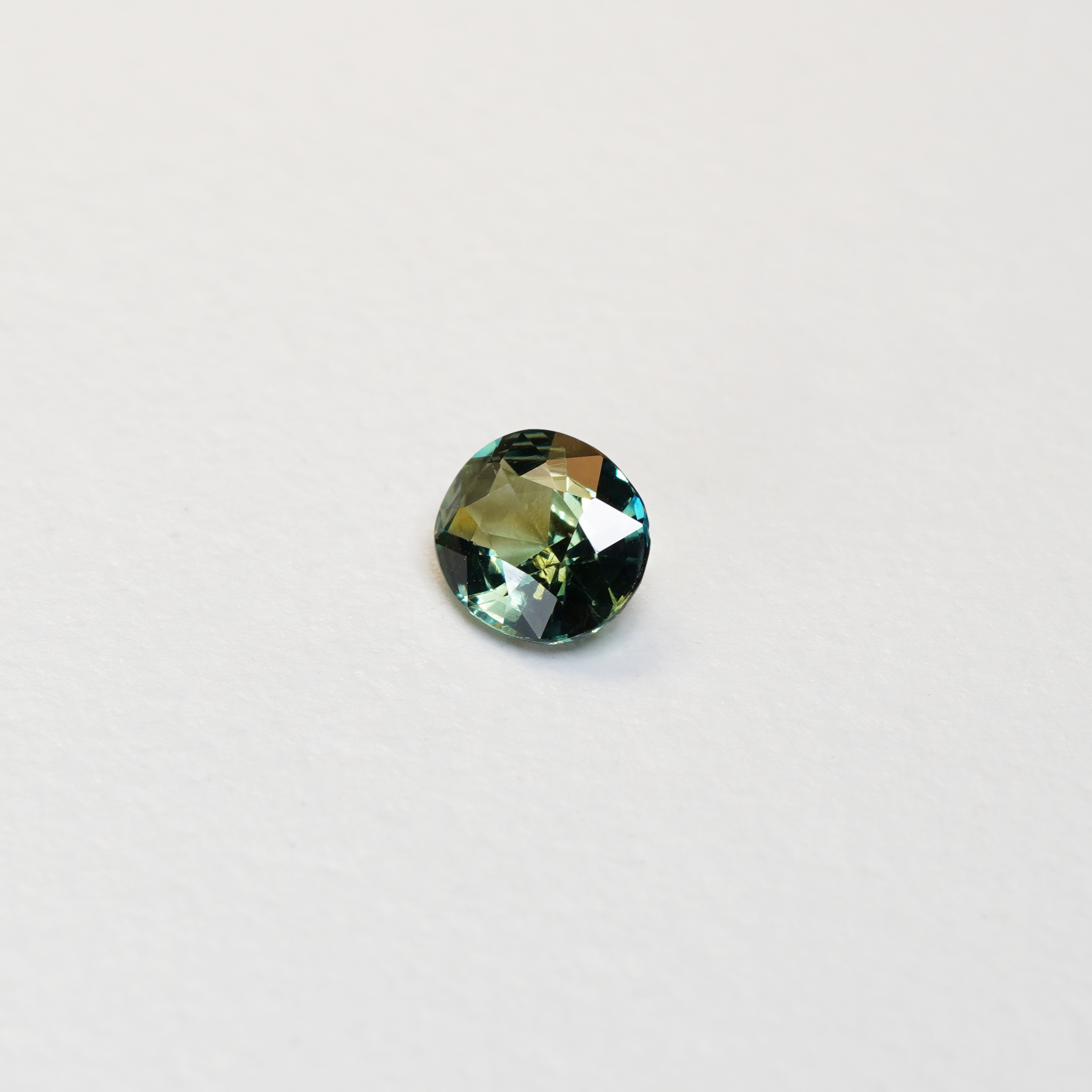 1.3 carat oval parti teal sapphire with mixed green and blue color.