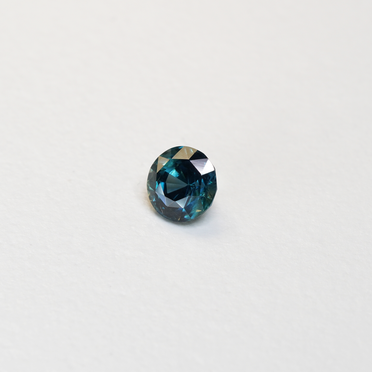 1.76 carat round parti teal sapphire with mixed green and blue color.