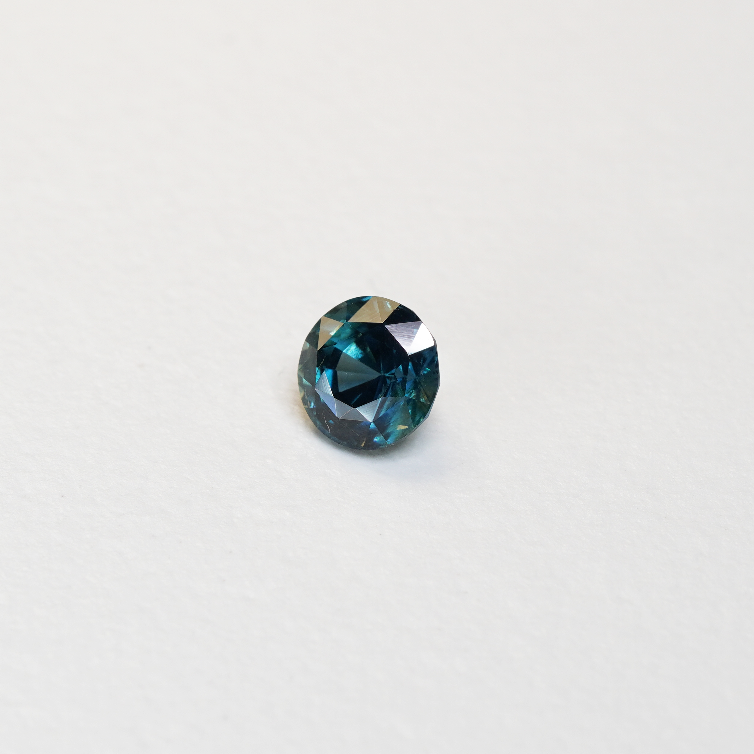 1.76 carat round parti teal sapphire with mixed green and blue color.