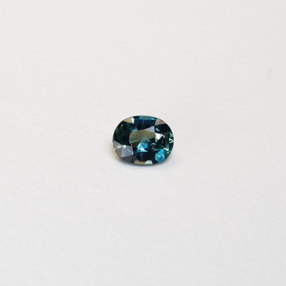 1.25 carat oval parti teal sapphire with mixed green and blue color.