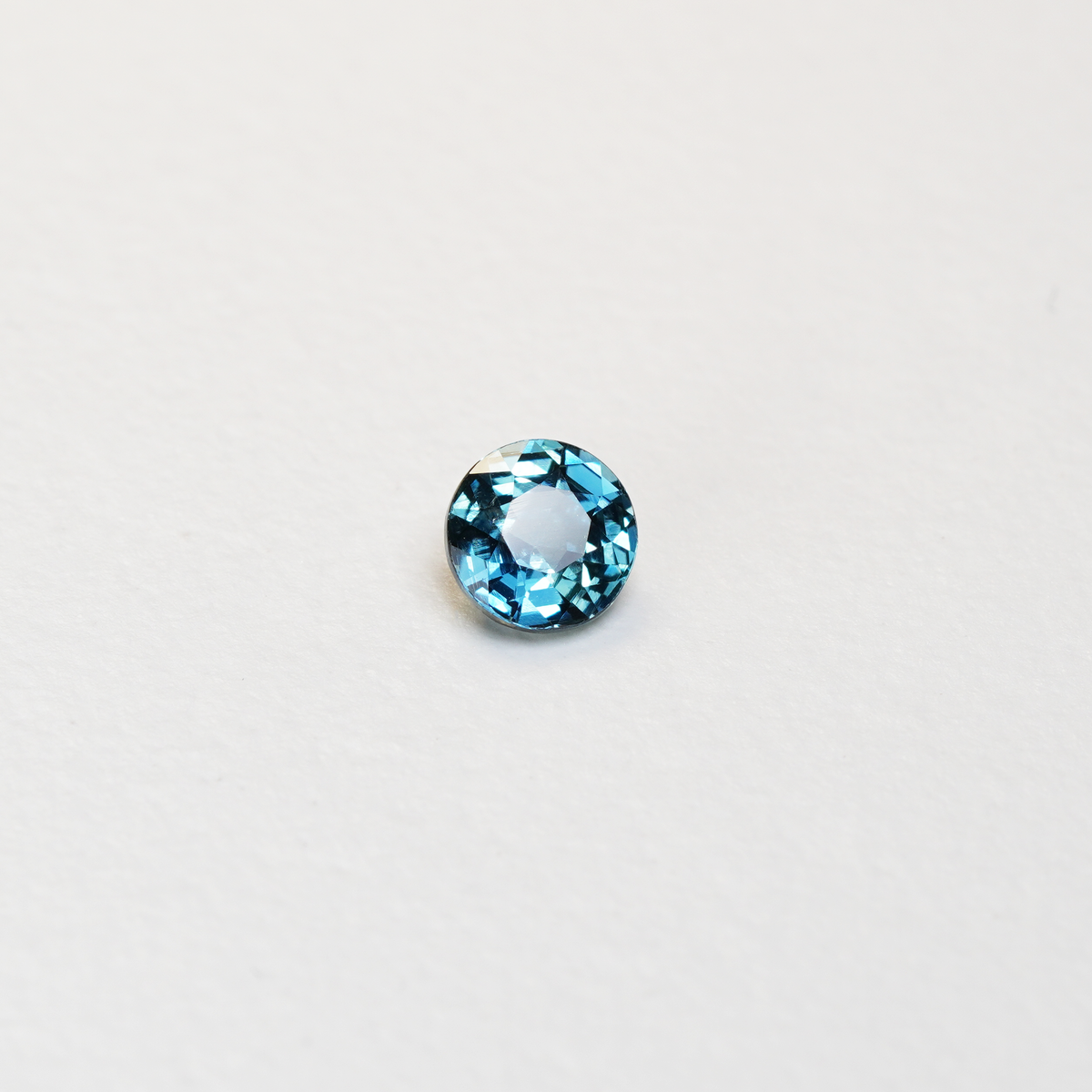 1 carat round parti teal sapphire with mixed green and blue color.