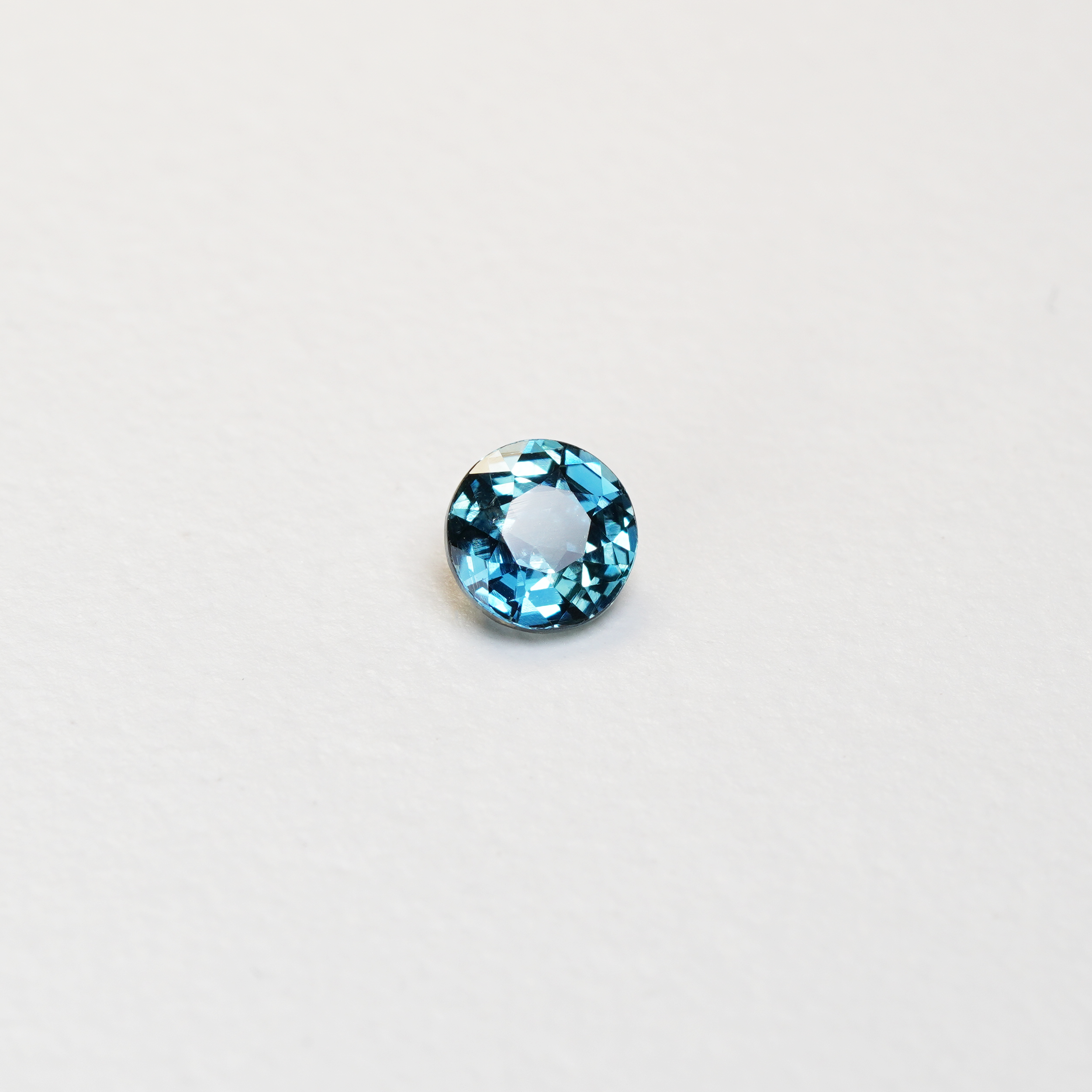 1 carat round parti teal sapphire with mixed green and blue color.