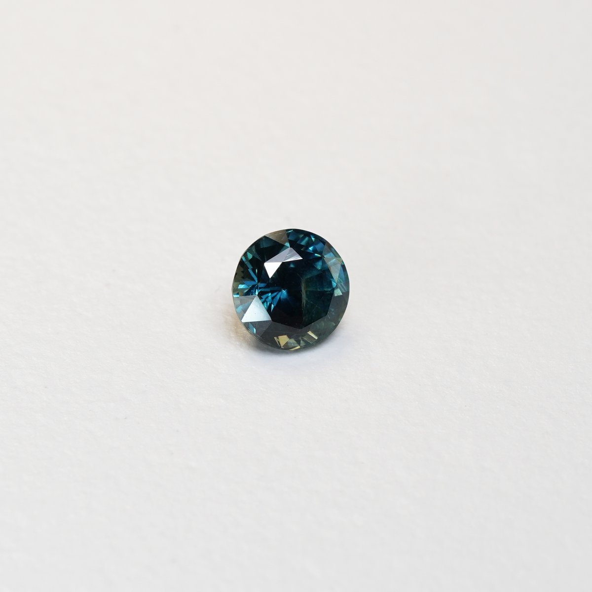 1.76 carat round parti teal sapphire with mixed green and blue color.