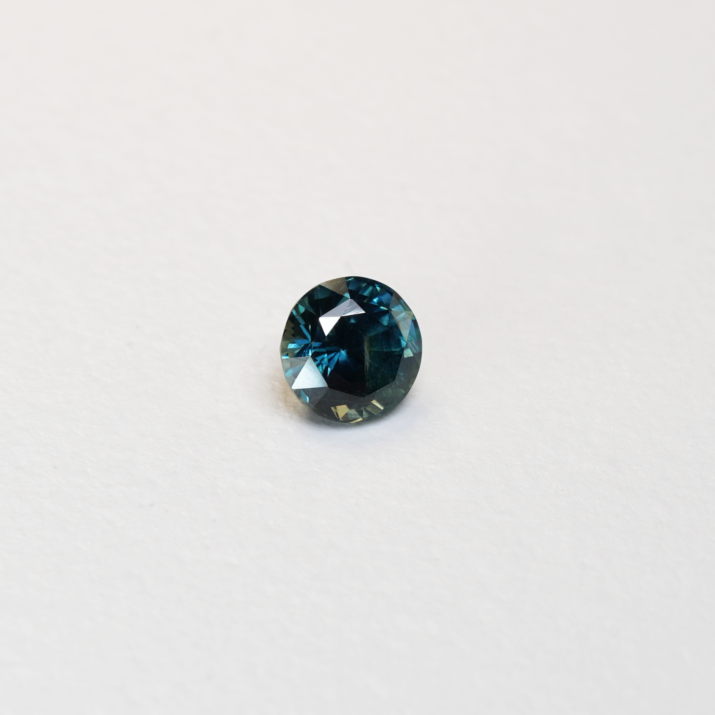 1.76 carat round parti teal sapphire with mixed green and blue color.
