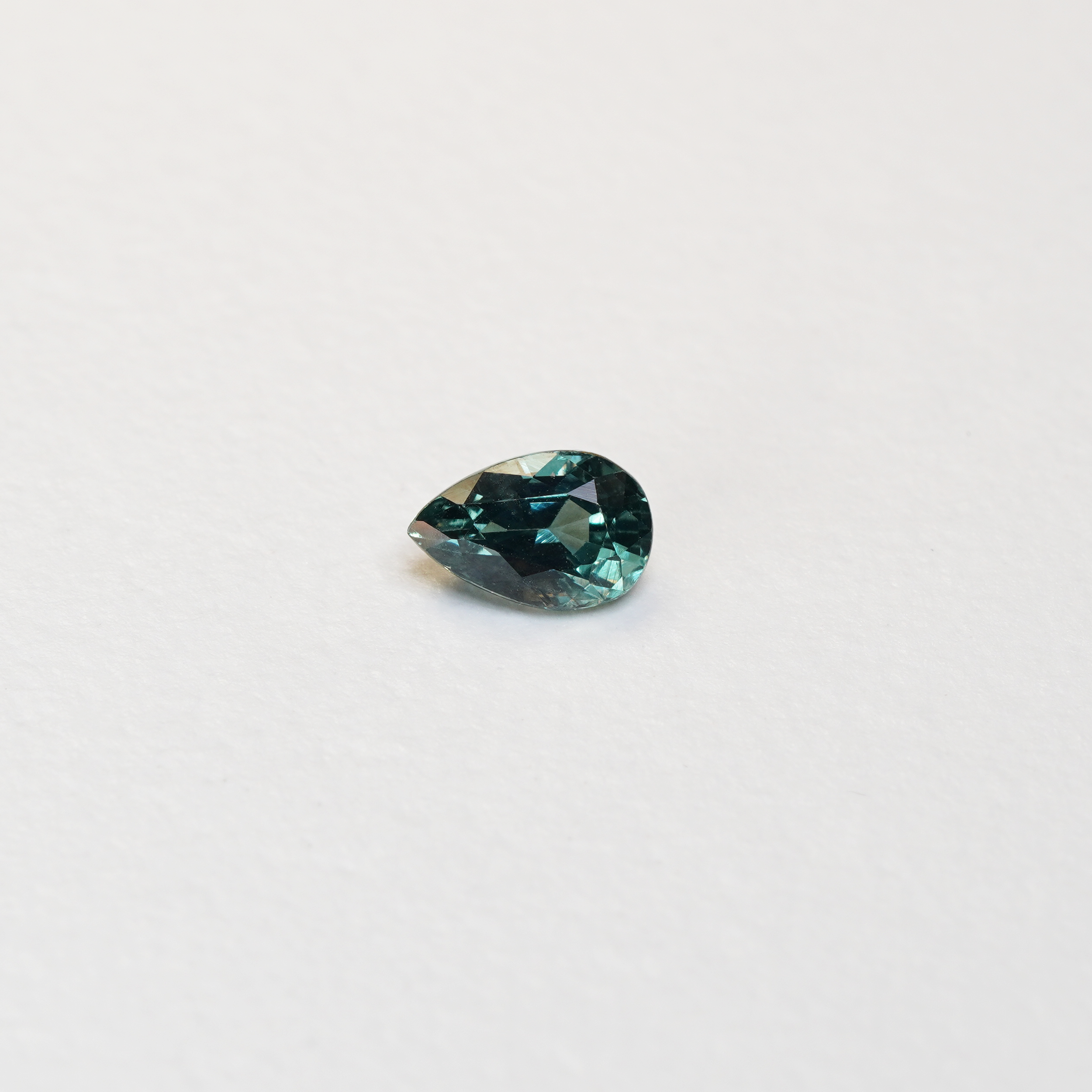 1.1 carat pear parti teal sapphire with mixed green and blue color.