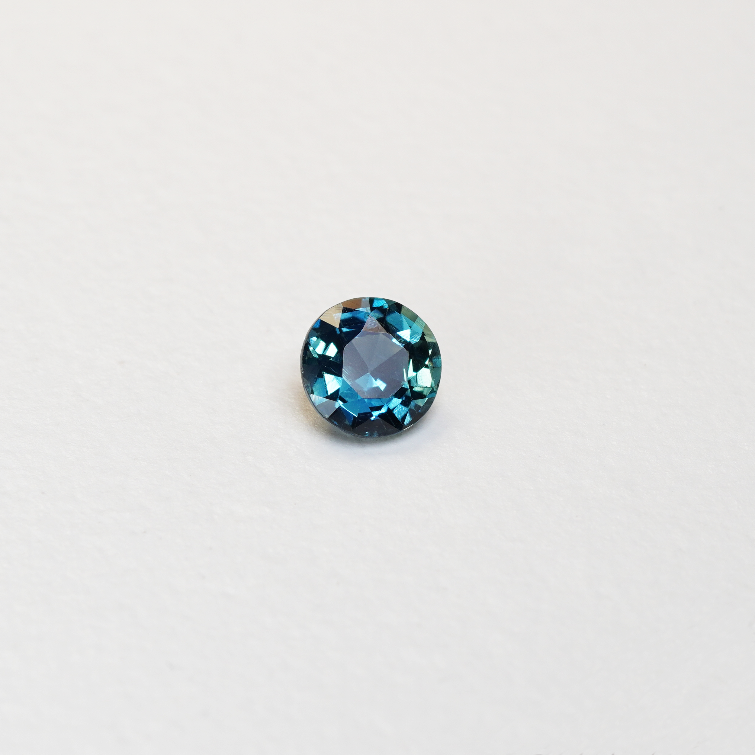 1.3 carat round parti teal sapphire with mixed green and blue color.
