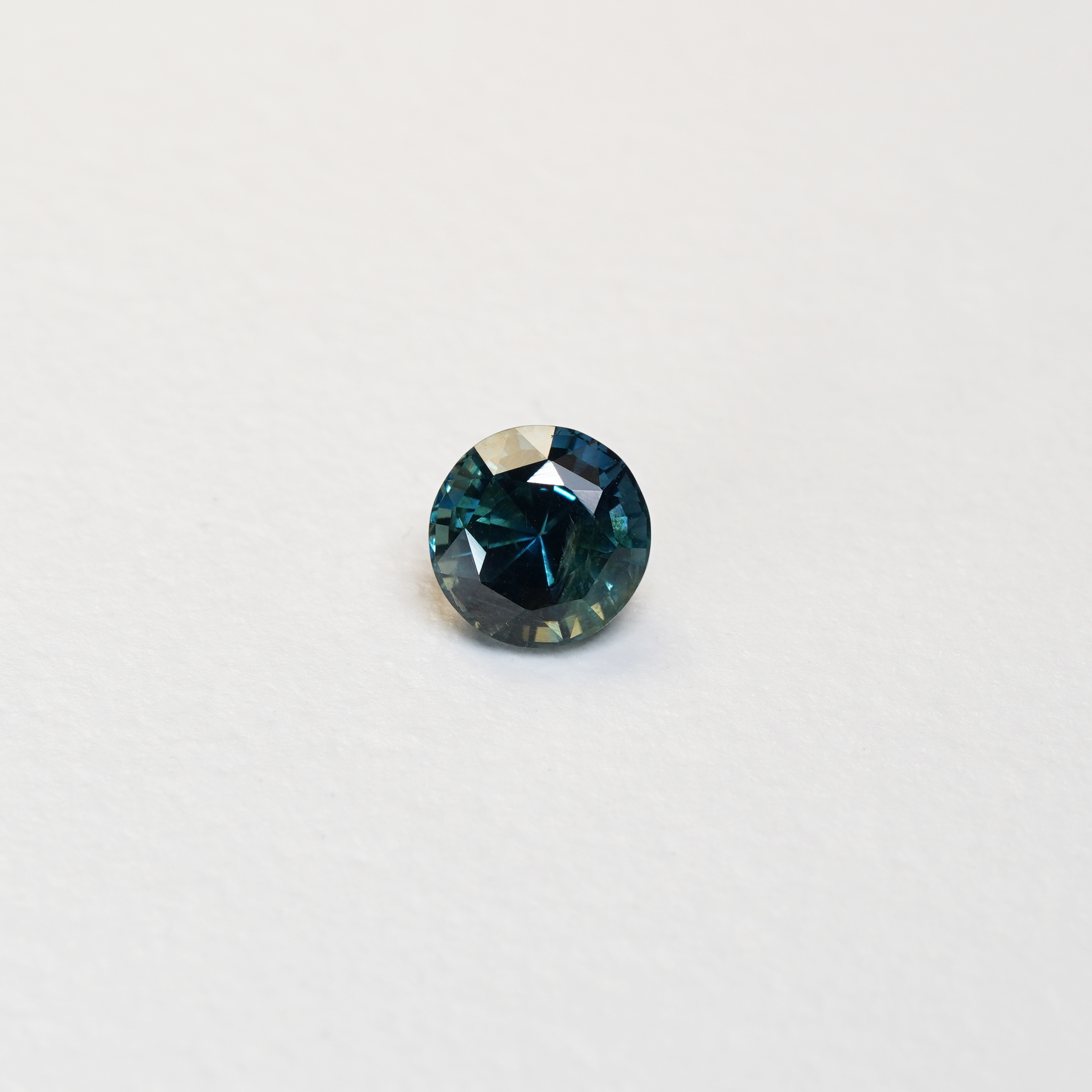 1.76 carat round parti teal sapphire with mixed green and blue color.