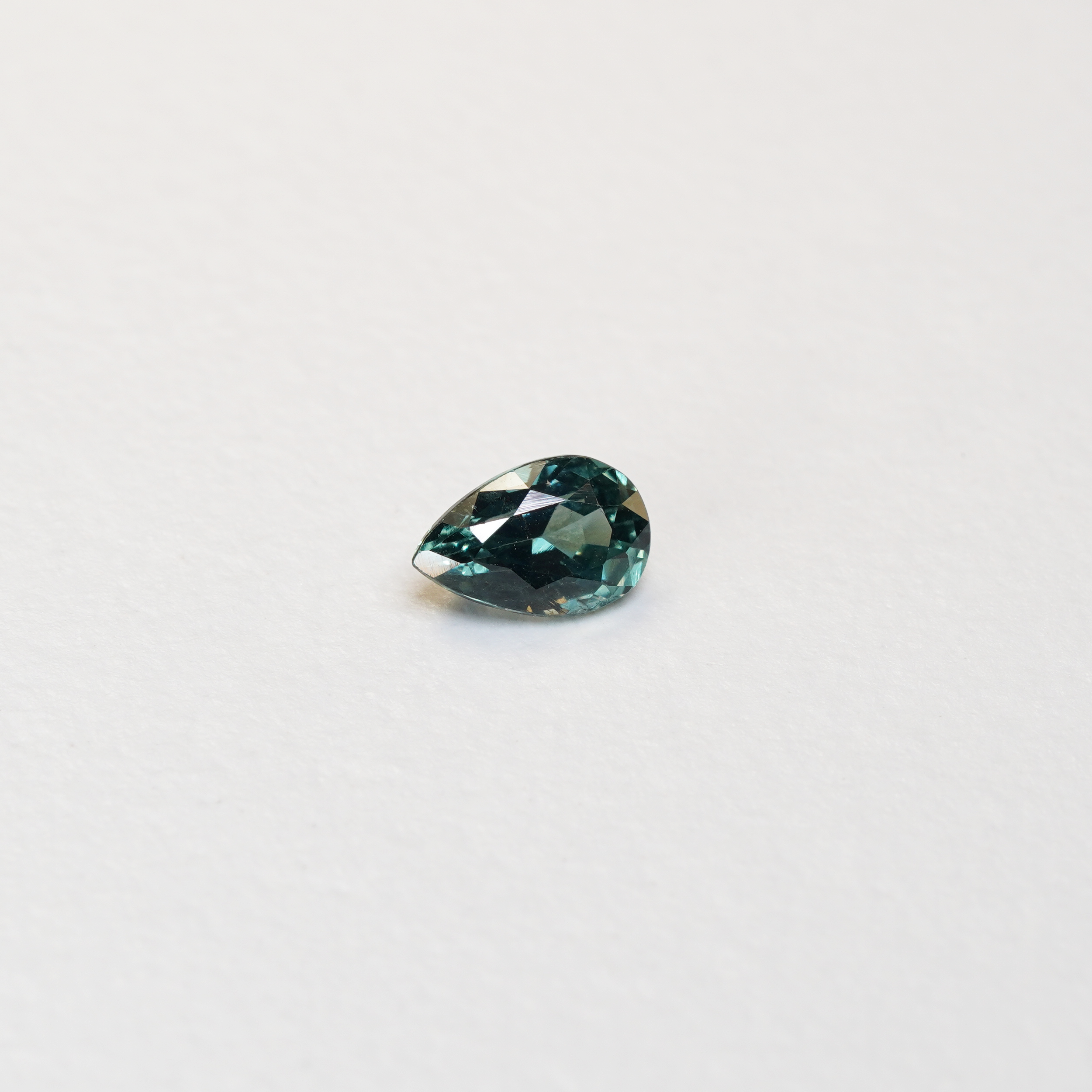 1.1 carat pear parti teal sapphire with mixed green and blue color.