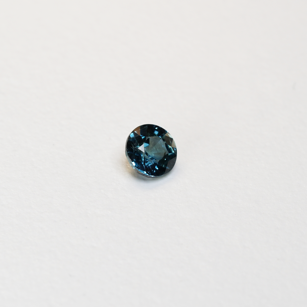 1 carat round parti teal sapphire with mixed green and blue color.