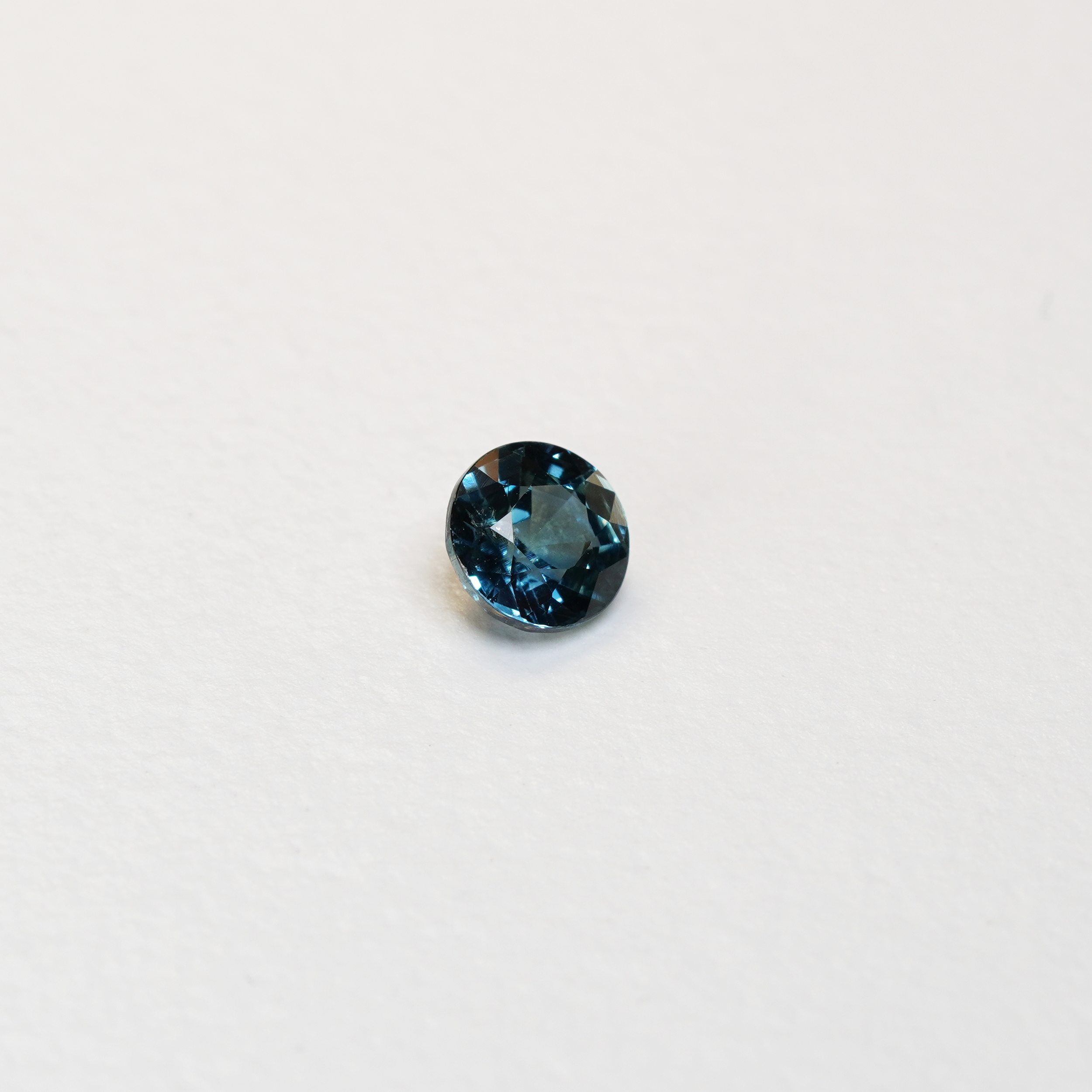 1 carat round parti teal sapphire with mixed green and blue color.