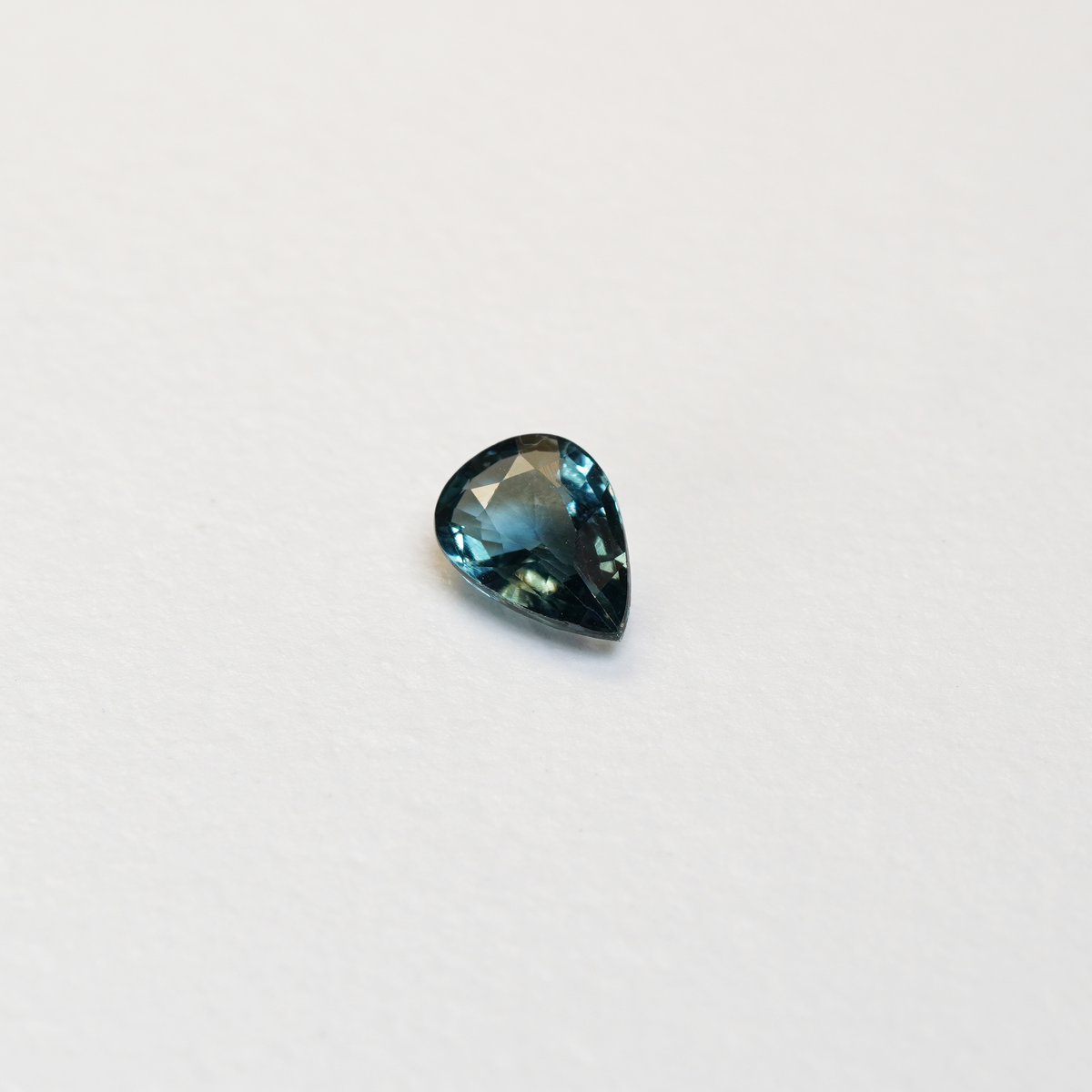 1 carat pear parti teal sapphire with mixed green and blue color.