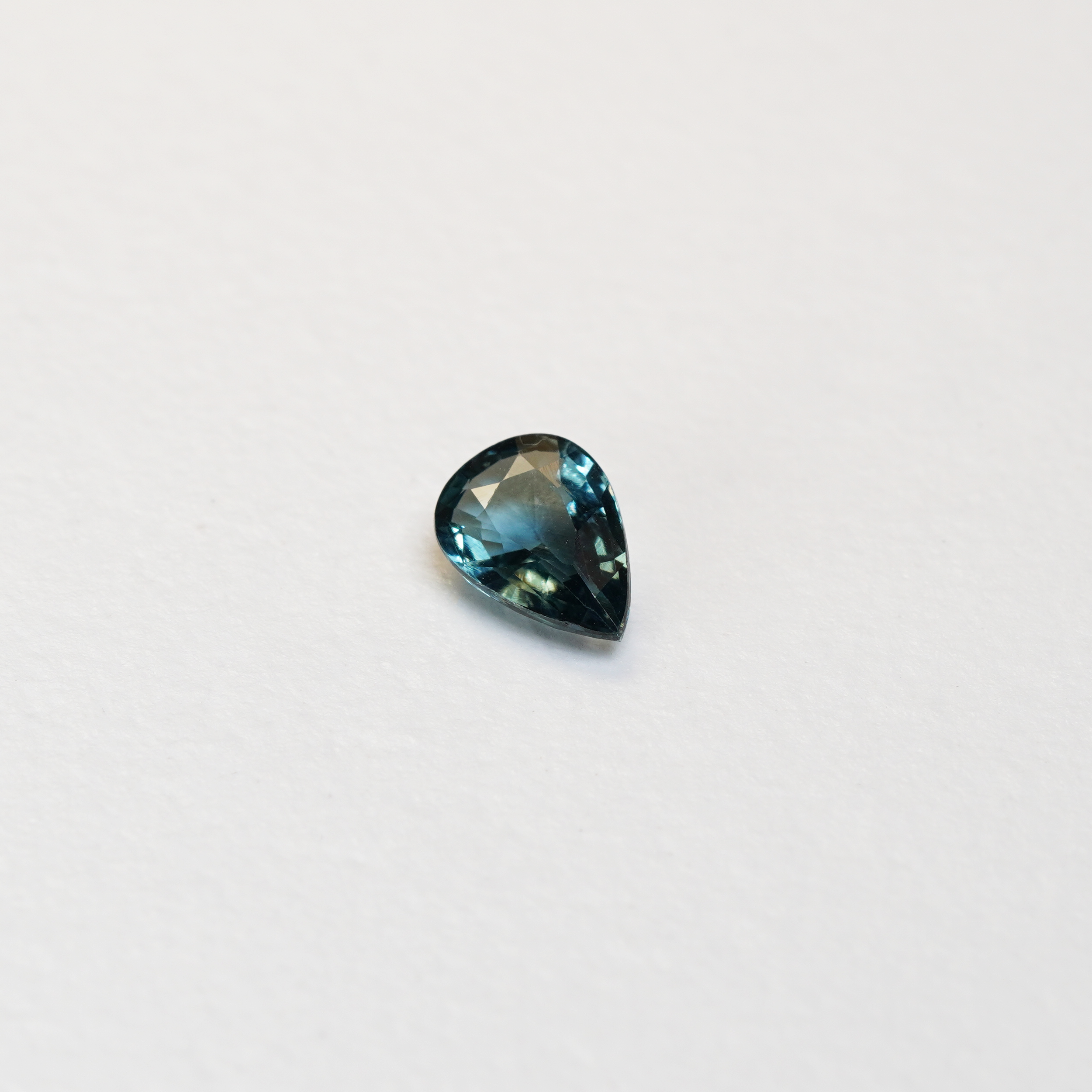 1 carat pear parti teal sapphire with mixed green and blue color.