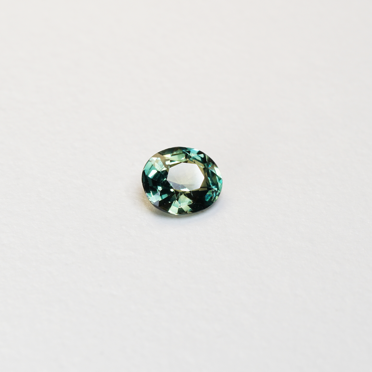 1.3 carat oval parti teal sapphire with mixed green and blue color.