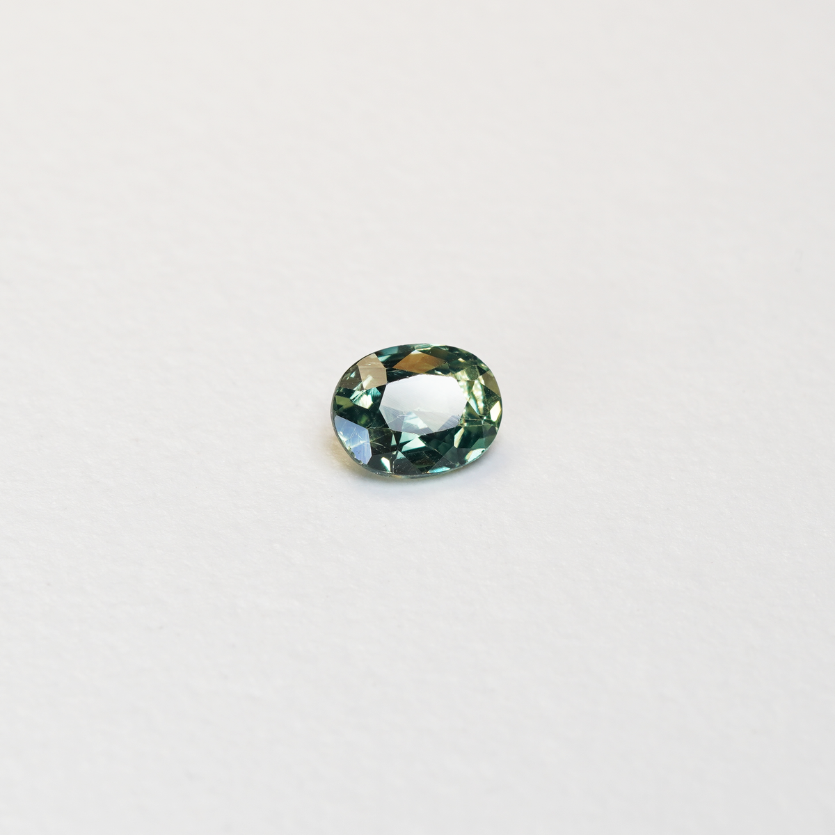 1.10 carat oval parti teal sapphire with mixed green and yellow color.