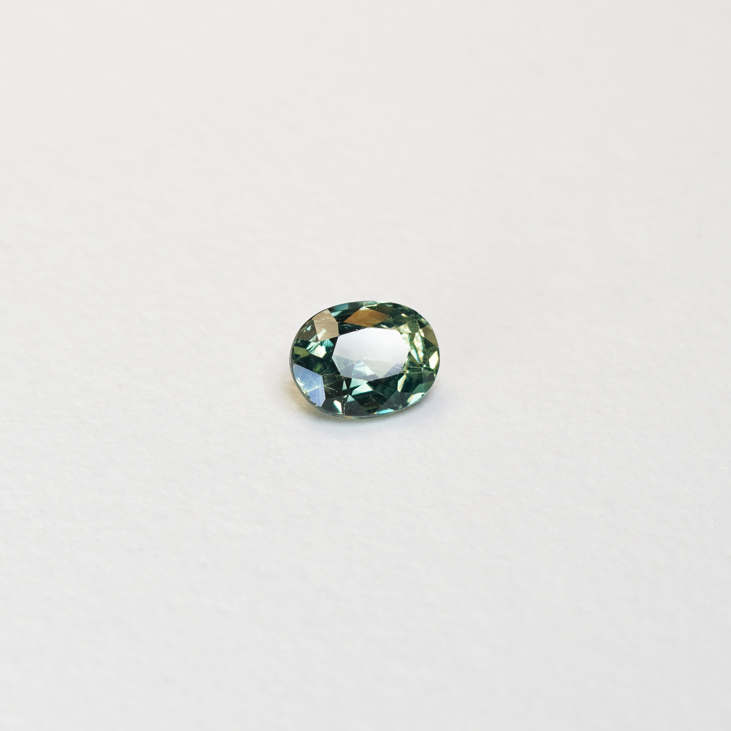 1.10 carat oval parti teal sapphire with mixed green and yellow color.