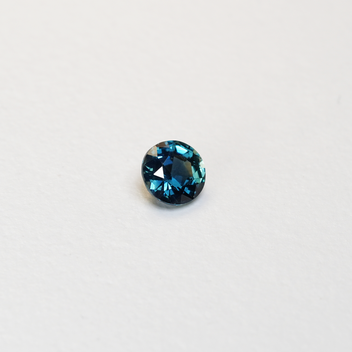 1.3 carat round parti teal sapphire with mixed green and blue color.