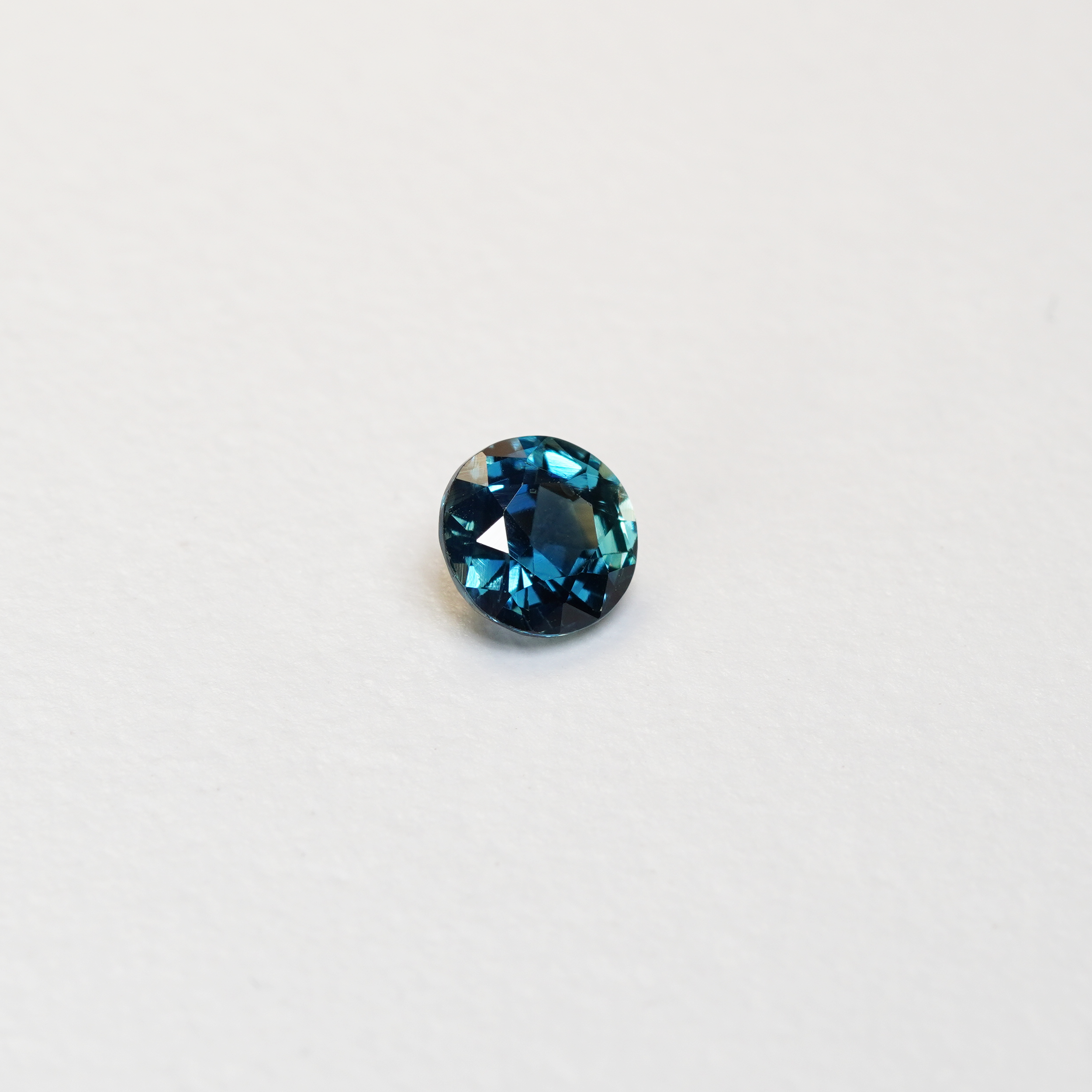 1.3 carat round parti teal sapphire with mixed green and blue color.