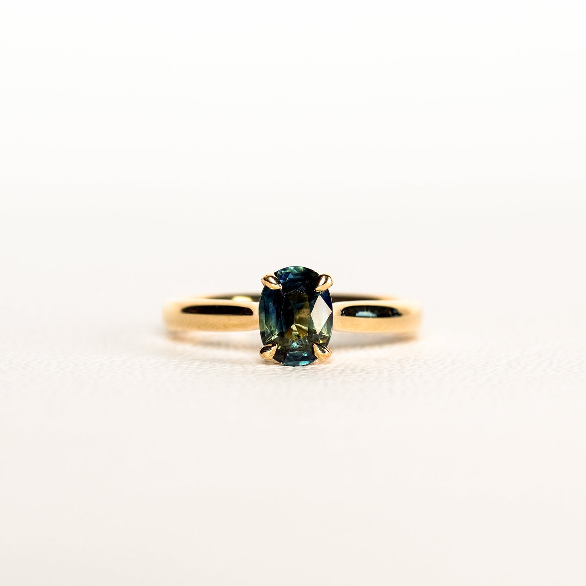 1.2 carat teal blue parti sapphire engagement ring with hidden halo in 18ct yellow gold. Cathedral settings 