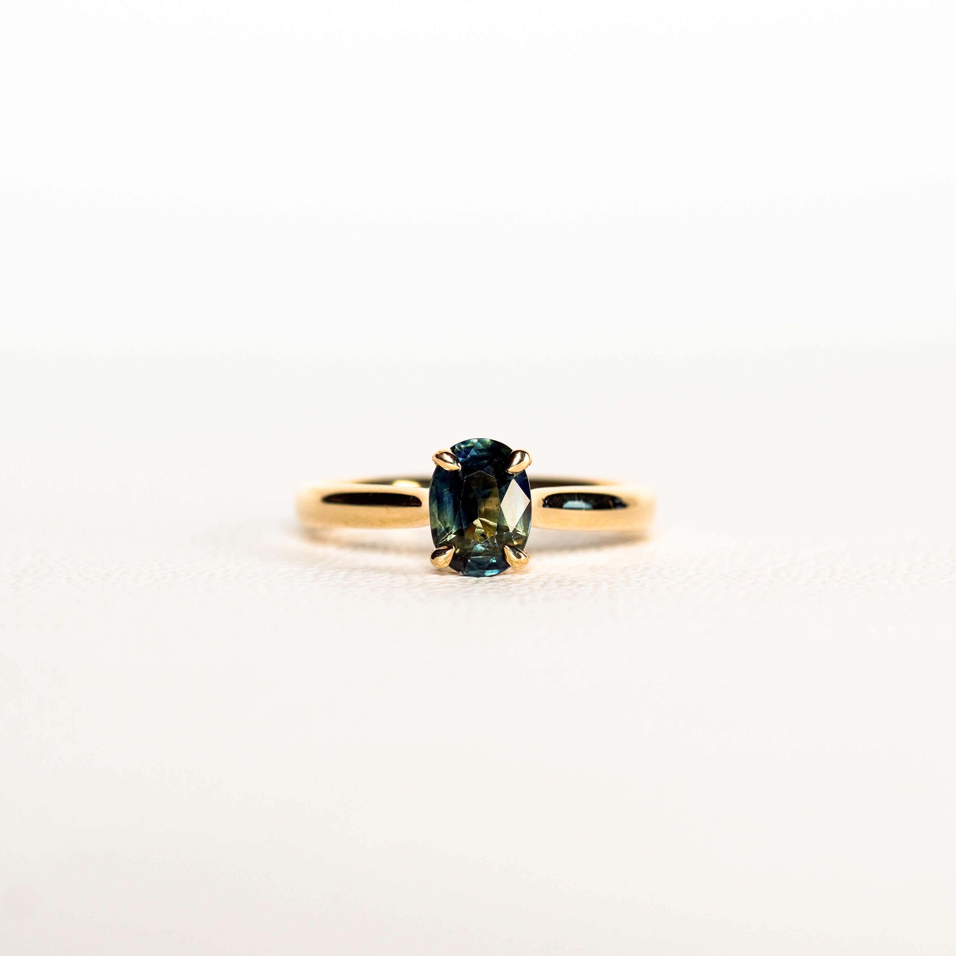 1.2 carat teal blue parti sapphire engagement ring with hidden halo in 18ct yellow gold. Cathedral settings 