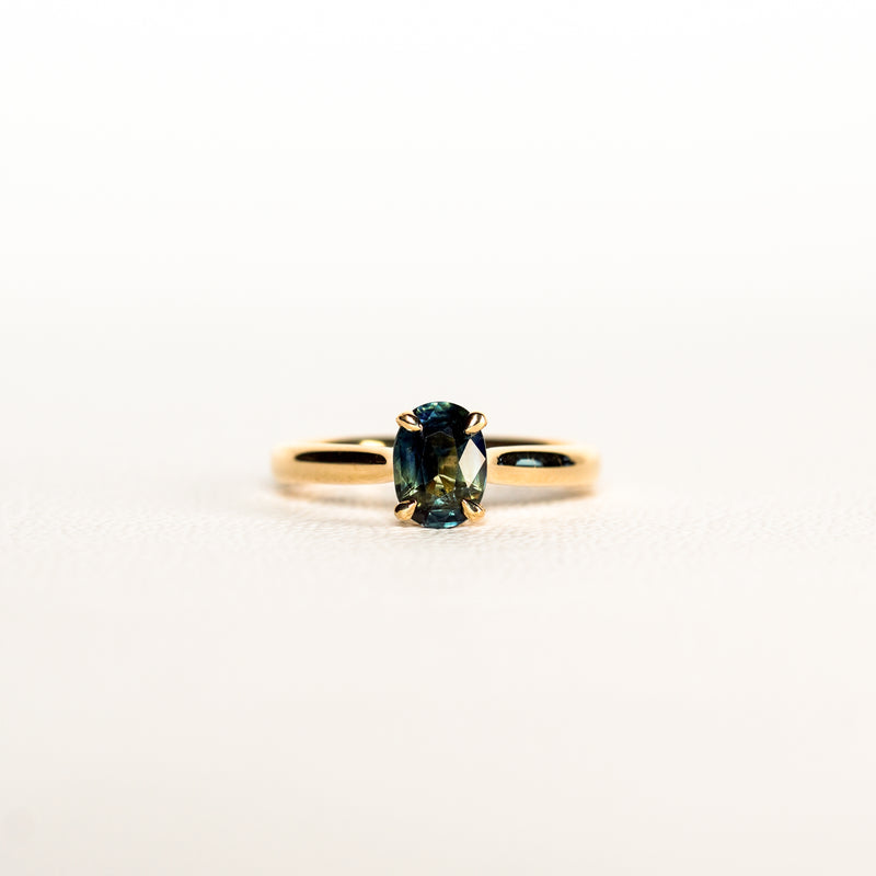 1.2 carat teal blue parti sapphire engagement ring with hidden halo in 18ct yellow gold. Cathedral settings 