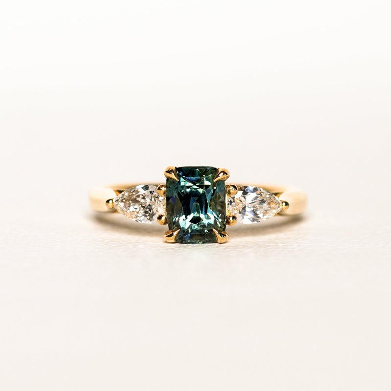 1.55 carat teal parti sapphire engagement ring with pair cut diamonds in 18ct yellow gold