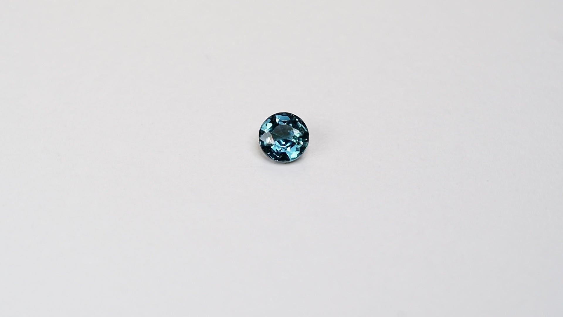 1 carat round parti teal sapphire with mixed green and blue color.