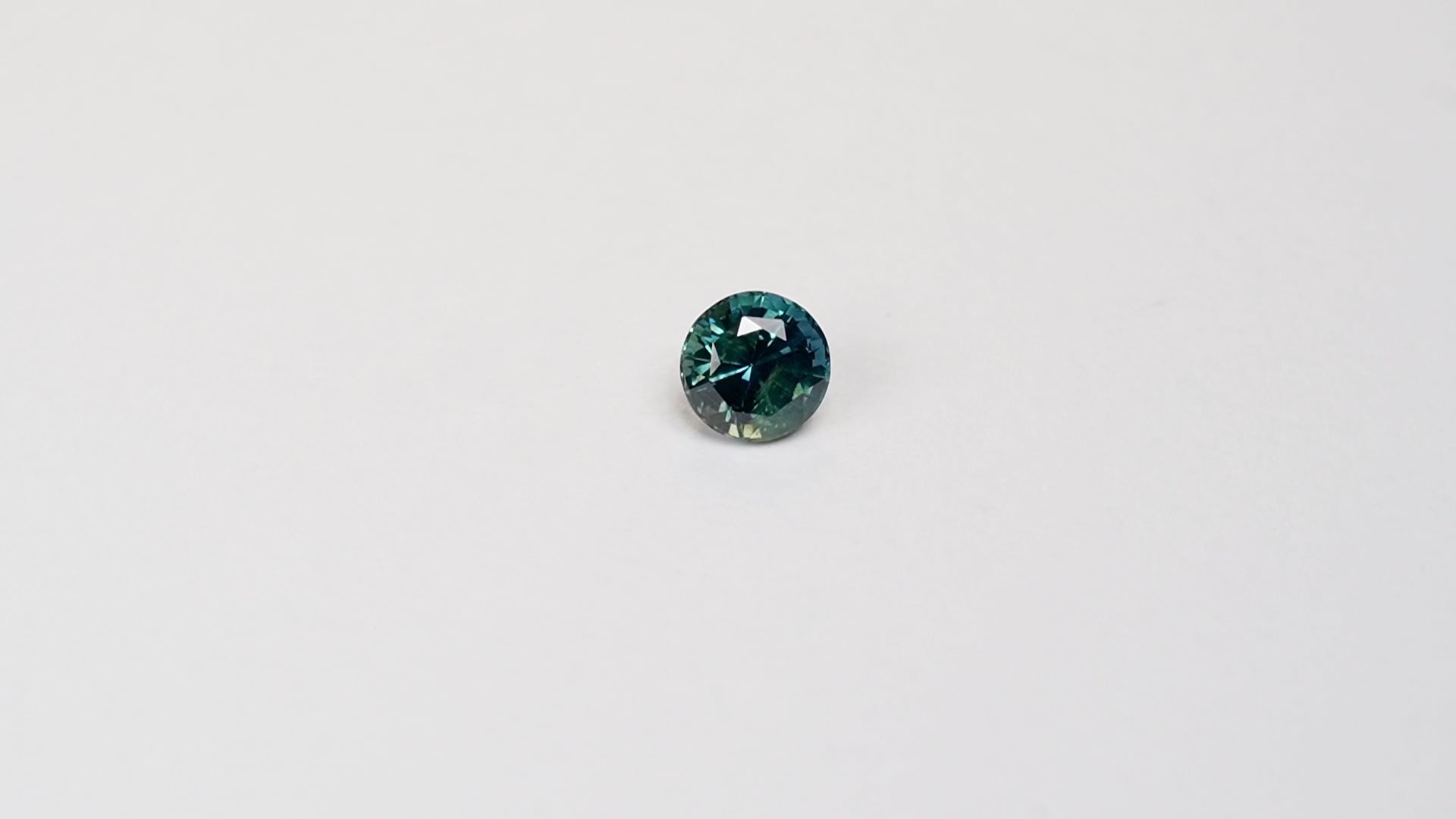 1.76 carat round parti teal sapphire with mixed green and blue color.