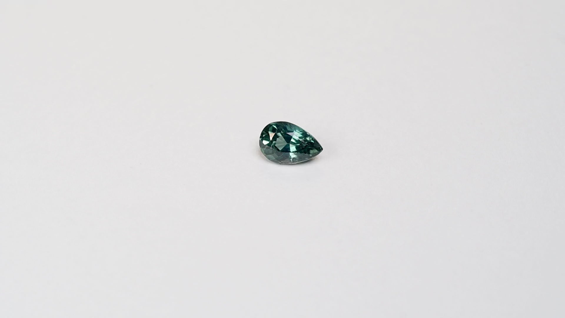 1.1 carat pear parti teal sapphire with mixed green and blue color.