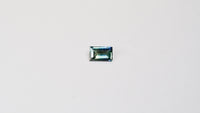 1.1 carat baguette parti teal sapphire with mixed green and blue color.