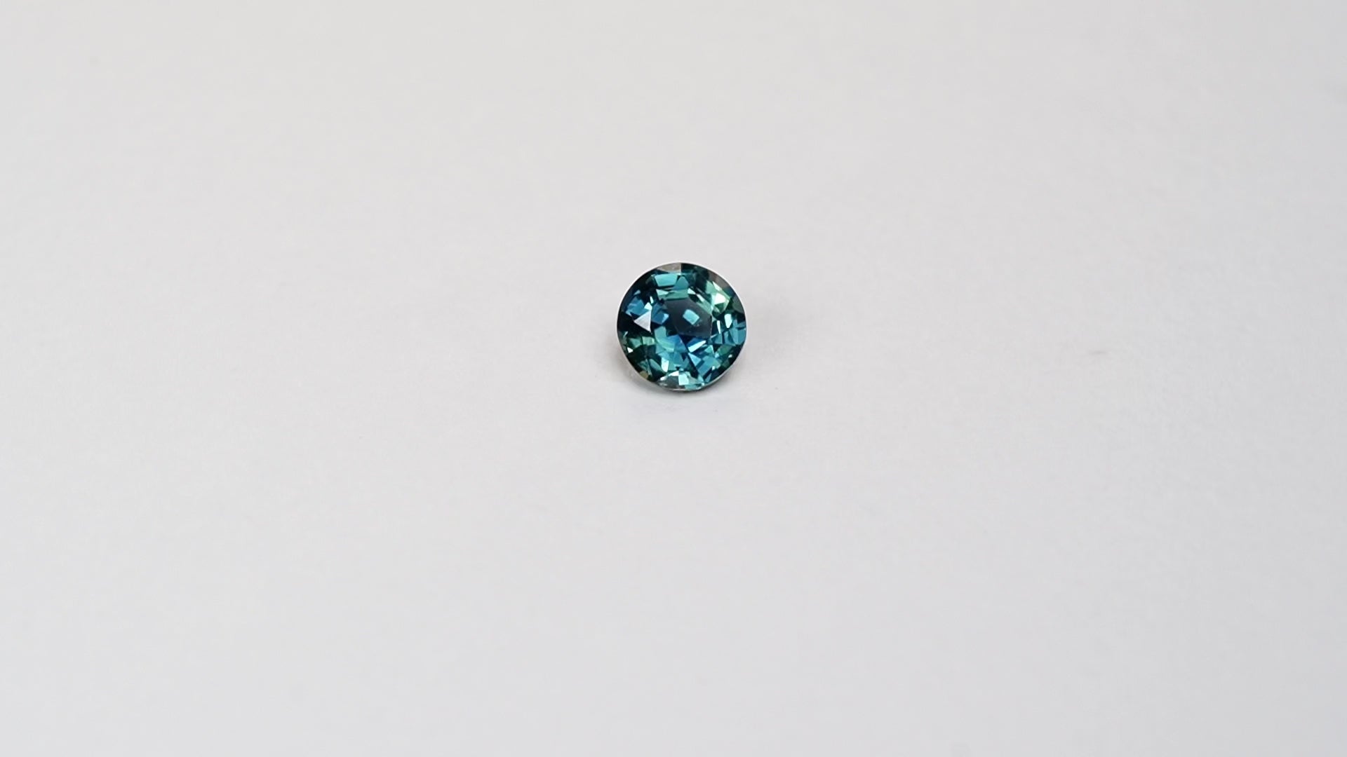 1.3 carat round parti teal sapphire with mixed green and blue color.